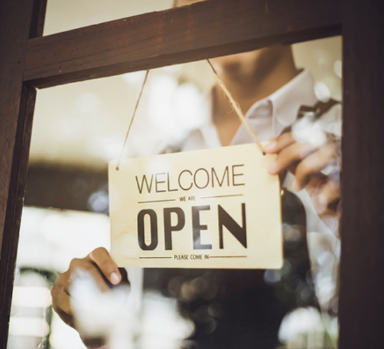 Man flips sign that says "Welcome - We are OPEN - Please Come In"