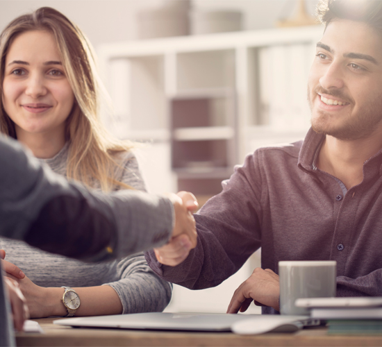 Two people shake hands in a deal, lady on the right smiling