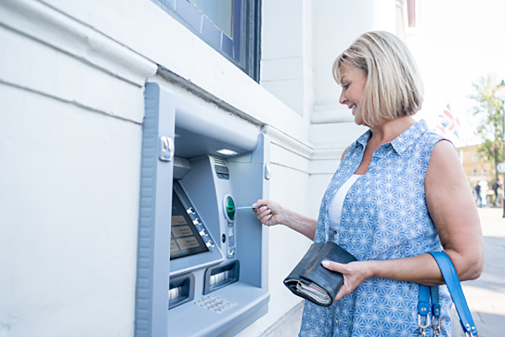 Woman withdrawing cash from an ATM - financial and business concepts.