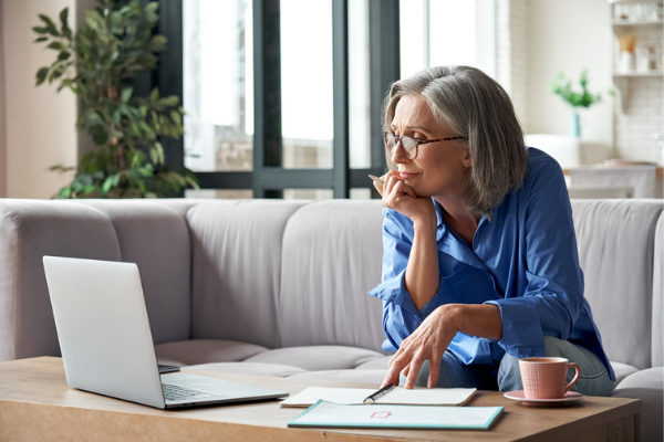 elder lady sitting on couch while looking at something on notebook computer