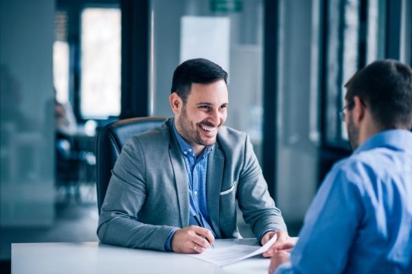 Man smiling while signing paper.