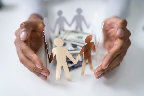 Hands surrounded Paper people gathered around money pile.