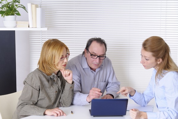 Three people looking at netbook computer while one lady points to something