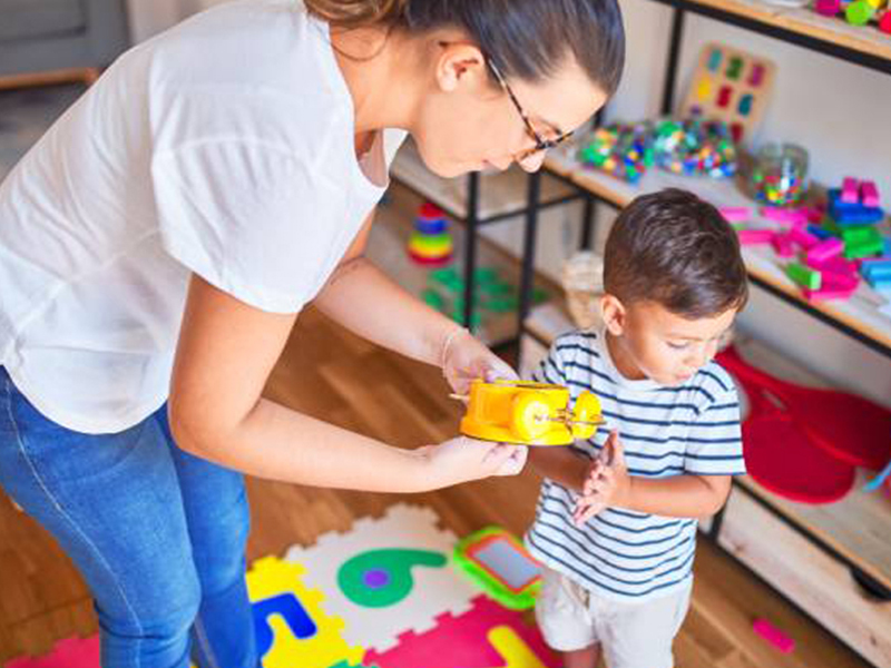 Ethnic family with two children carrying boxes and plant in new home on moving day. High angle view of happy smiling daughters helping mother and father with cardboard boxes in new house. Top view of excited kids having fun walking up stairs running to their rooms while parents holding boxes.